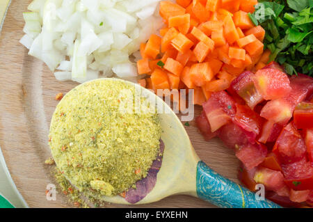 Kochlöffel mit Gewürzen und bunten geschnittene Gemüse auf dem Brett bereit für das Kochen Stockfoto