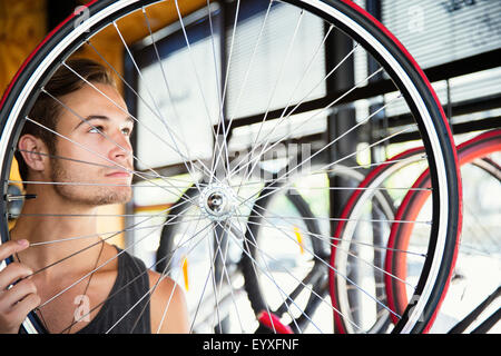 Junger Mann Prüfung Speichen Rad im Fahrradshop Stockfoto