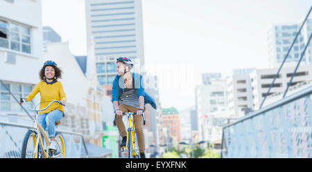 Freunde mit Helmen auf Fahrrädern über städtische Steg Stockfoto
