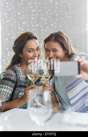 Frauen mit weißen Wein nehmen Selfie mit Kamera-Handy im restaurant Stockfoto