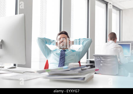 Entspannt Geschäftsmann lehnte sich mit den Händen hinter dem Kopf am Computer im Büro Stockfoto