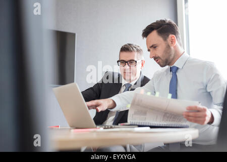 Geschäftsleute mit Bericht auf Laptop im Büro arbeiten Stockfoto