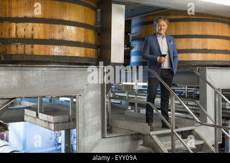 Porträt zuversichtlich Winzer mit Rotwein auf Plattform im Weingut Keller Stockfoto
