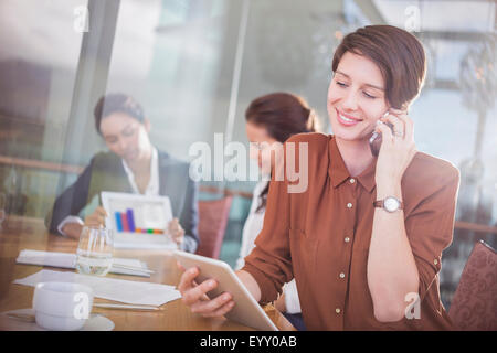 Geschäftsfrau, reden über Handy und mit digital-Tablette in Büro Stockfoto