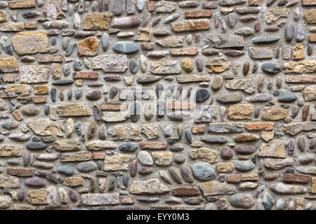 Eine alte Mauer verziert mit Steinen und Kies in verschiedenen Größen, mit unregelmäßigen Anordnung. Stockfoto