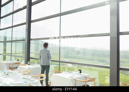 Mann stand am sonnigen Fenster im Weingut Speisesaal Stockfoto