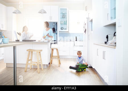 Frauen in Küche kochen, während junge mit Spielzeug-Traktor auf Etage spielt Stockfoto