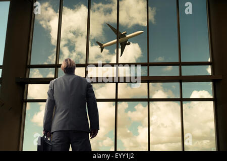 Kaukasische Geschäftsmann bewundern Flugzeug vom Flughafen windows Stockfoto