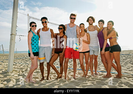 Freunde lächelnd in der Nähe von Volleyballnetz am Strand Stockfoto