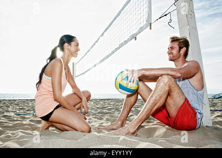 Freunde sprechen in der Nähe von Volleyballnetz am Strand Stockfoto