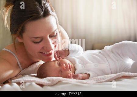 Mutter bewundernden neugeborenes Baby auf Bett Stockfoto