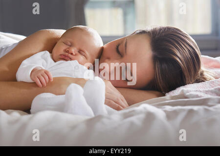 Mutter umarmt neugeborenes Baby auf Bett Stockfoto
