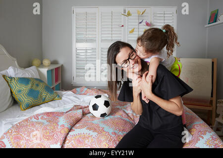 Kaukasische Mutter und Tochter küssen im Schlafzimmer Stockfoto