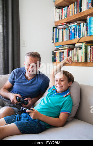 Kaukasische Vater und Sohn spielen von Videospielen auf sofa Stockfoto