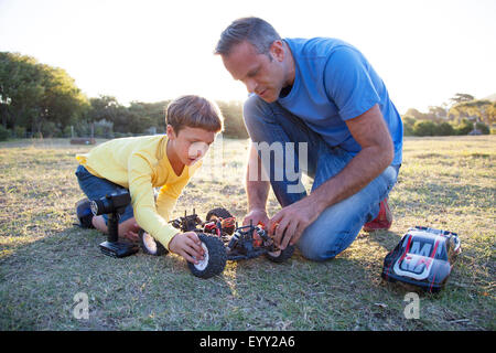 Kaukasische Vater und Sohn spielen mit ferngesteuerten Autos im Feld Stockfoto