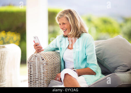 Kaukasische Frau mit Handy auf Sofa im freien Stockfoto