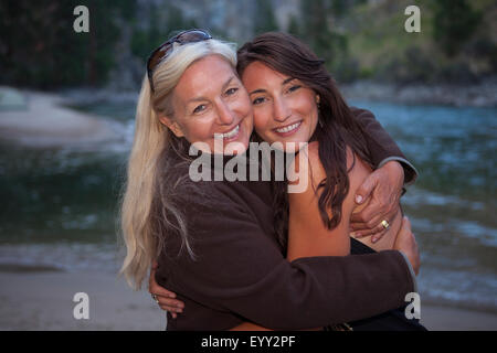 Kaukasische Mutter und Tochter in der Nähe von See umarmt Stockfoto