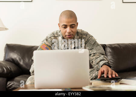 Gemischte Rassen Soldat mit Laptop auf dem Sofa im Wohnzimmer Stockfoto