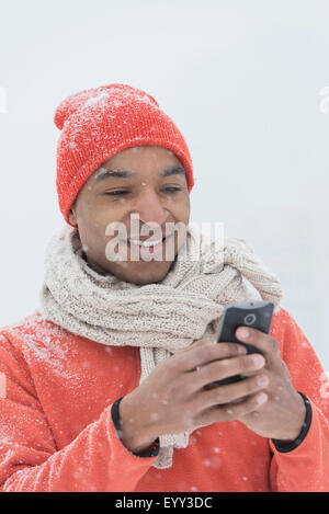 Schwarzer Mann mit Handy im Schnee Stockfoto