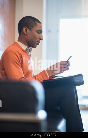 Schwarze Geschäftsmann mit Handy im Büro lobby Stockfoto
