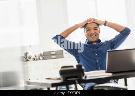 Schwarze Geschäftsmann lächelnd am Schreibtisch Stockfoto