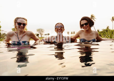 Lächelnde Frauen entspannen im Infinity-pool Stockfoto