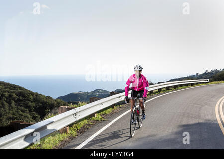 Kaukasische Frau Radfahren auf abgelegenen Bergstraße Stockfoto