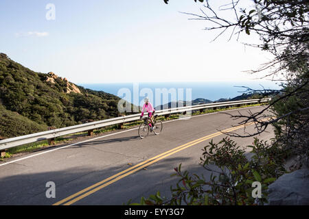 Kaukasische Frau Radfahren auf abgelegenen Bergstraße Stockfoto