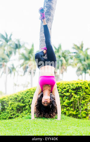 Chinesische Frau tun Handstand gegen Baum im park Stockfoto