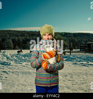 Kaukasische Mädchen umarmt Kaninchen in schneebedecktes Feld Stockfoto