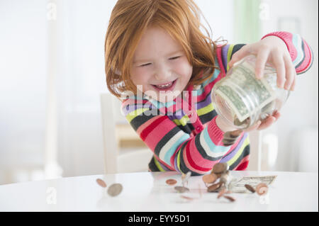 Kaukasische Mädchen Geld aus Änderung Glas gießen Stockfoto