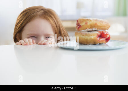 Kaukasische Mädchen Donuts auf Tabelle einsehen Stockfoto