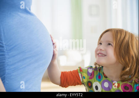 Kaukasische Mädchen berühren Bauch der schwangeren Mutter Stockfoto