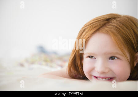 Lächelndes kaukasische Mädchen auf Bett Stockfoto