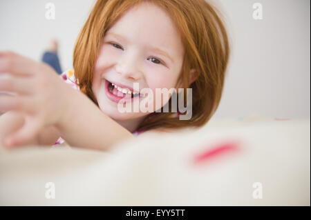 Lächelndes kaukasische Mädchen auf Bett Stockfoto