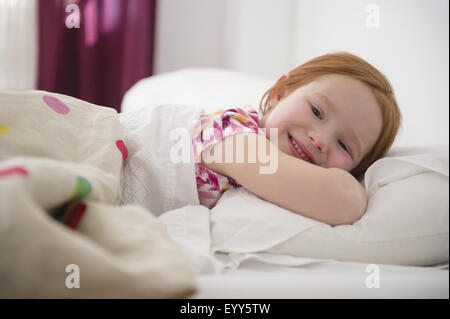 Lächelndes kaukasische Mädchen im Bett Stockfoto