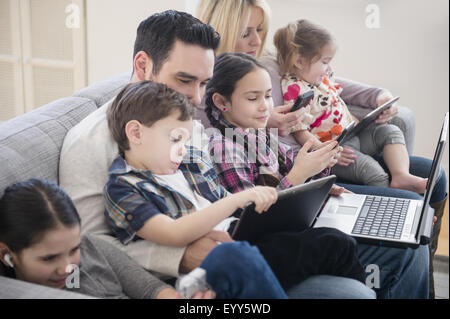 Kaukasische Familie mit Hilfe von Technologie auf sofa Stockfoto