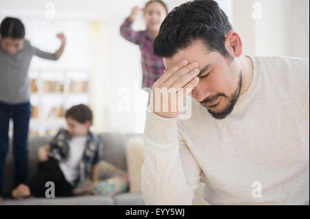 Gestresste kaukasischen Vater mit schreien Kinder im Wohnzimmer Stockfoto
