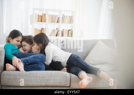 Kaukasische Bruder und Schwestern Flüstern auf sofa Stockfoto