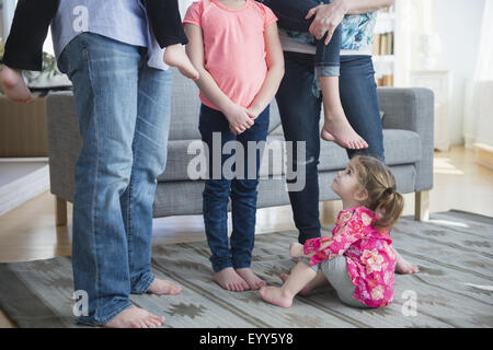 Kaukasische Mädchen sitzen unter Familie im Wohnzimmer Stockfoto