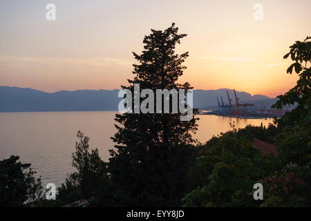 Rijeka, Kroatien. Sonnenuntergang über den Hafen und die Werft Krane mit den Bergen der Halbinsel Istrien im Hintergrund Stockfoto