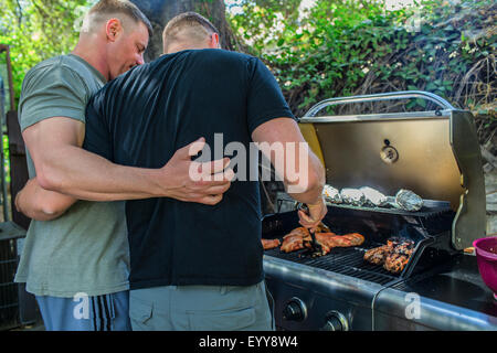 Gay paar Grillen von Lebensmitteln im Hinterhof Stockfoto