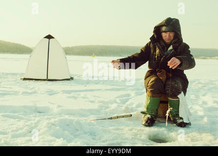 Kaukasischen Mann Eisfischen auf abgelegenen See Stockfoto