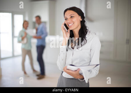 Grundstücksmakler, reden über Handy mit paar in neues Zuhause Stockfoto