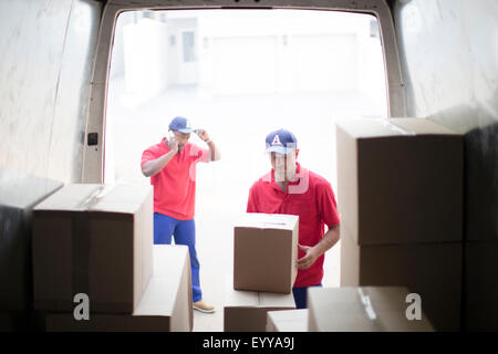 Lieferung Männer entladen Pakete in van Stockfoto