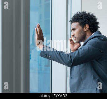 Hispano-Amerikaner Geschäftsmann reden über Handy am Bürofenster Stockfoto