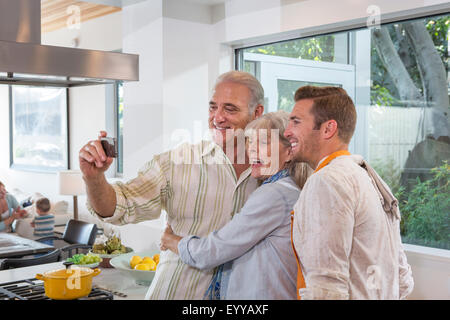 Kaukasische Eltern und Sohn nehmen Selfie in Küche Stockfoto