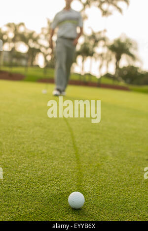 Kaukasischen Mann zu Fuß, Golfball auf Golfplatz grün Stockfoto