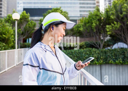 Asiatische Läufer mit Handy in Stadt Stockfoto