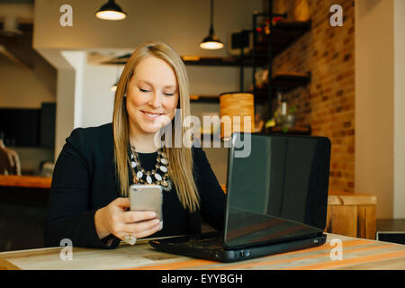 Kaukasische Geschäftsfrau mit Laptop und Handy im café Stockfoto